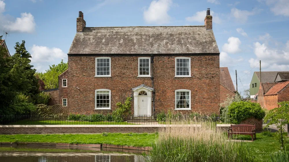 Prospect House, a red-brick Georgian farmhouse, seen across the village duck pond